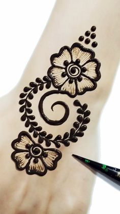 a hand with a hendi design on it and a black marker next to it