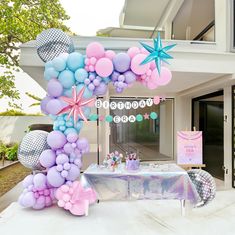 a table topped with balloons and starfishs next to a party sign in front of a house