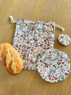 a flowered bag and two pieces of bread on a wooden table