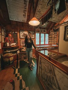 a woman standing in the middle of a room with lots of pictures on the walls