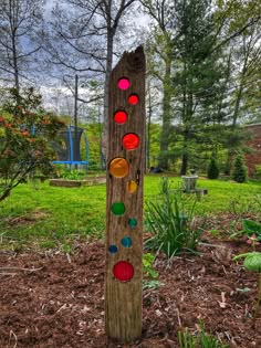 a wooden sculpture in the middle of a park with colorful circles on it's side