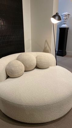 a white round couch with three pillows on it