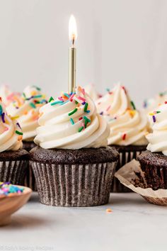 cupcakes with white frosting and sprinkles are on a table