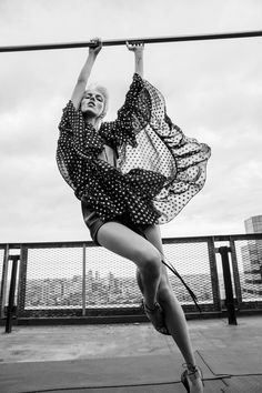 a woman is hanging upside down on a pole