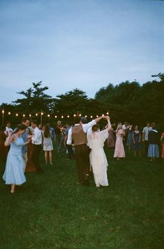 a group of people standing on top of a lush green field next to each other