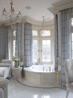 an elegant bathroom with chandelier, tub and white chair in it's center