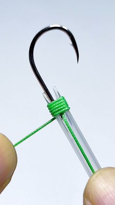 a person holding a fishing hook with green string