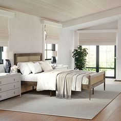 a bedroom with white walls and wooden floors, along with a large bed in the center