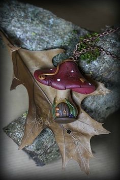 a red and brown leaf sitting on top of a rock next to a tree branch