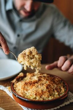 a man is eating macaroni and cheese from a dish on a plate with a spoon