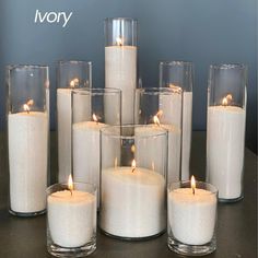 a group of white candles sitting on top of a table next to eachother