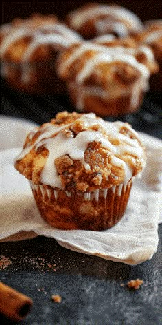 a muffin with white icing sitting on top of a napkin next to other muffins