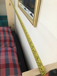 a measuring tape is in front of a bed with a painting on the wall behind it