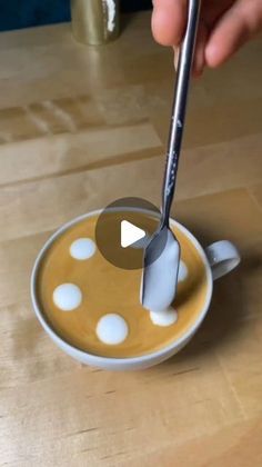 a person using a spoon to stir something in a cup on a saucer with white polka dots