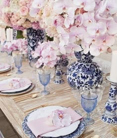 the table is set with blue and white plates, pink napkins, and flowers