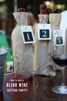 three wine bottles with tags on them sitting next to a glass of wine and a bucket