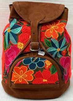 the back side of a backpack with colorful flowers on it and a brown leather strap