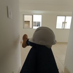 a person wearing a hard hat sitting on the floor in front of a white wall