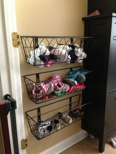 two baskets are hanging on the wall with shoes in them and one is holding several pairs of slippers