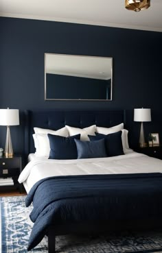 a bedroom with blue walls and white bedding in the center, along with a large mirror on the wall