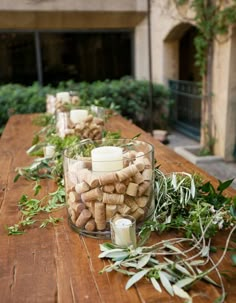 a wooden table topped with candles and greenery