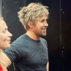 a man with blonde hair standing next to a woman