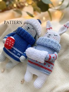 two crocheted stuffed animals laying on top of a white blanket next to a christmas tree