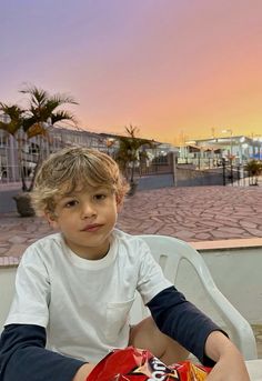 a young boy sitting at a table with a bag of chips in front of him