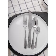 a white plate topped with silverware on top of a black and white table cloth