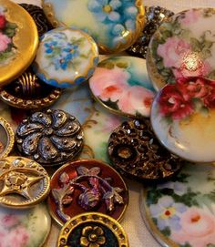 there are many different types of buttons on the table together, including one that has been decorated with flowers