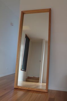 an empty room with a large mirror on the wall and wood flooring in front of it