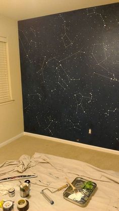 a room with some paint and tools on the floor next to a wall that has stars painted on it