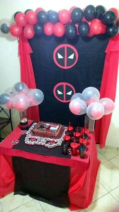 a table with balloons, cake and decorations for a deadpool themed birthday party on it