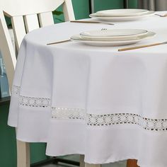 the table is set with white plates and silverware on it's placemats