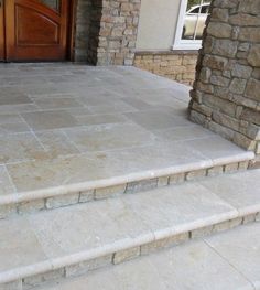 a dog is sitting on the front steps of a house that has stone steps leading up to it