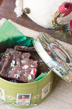 a green tin filled with brownies and candy canes on top of a table