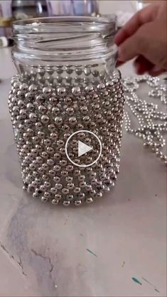 a mason jar filled with lots of silver beaded balls and a video player playing on the screen