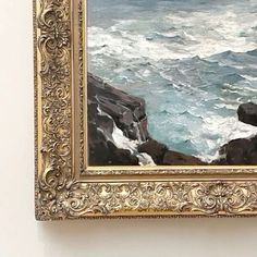 a painting hanging on the wall next to a white wall with an ocean scene in it