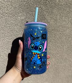 a hand holding a blue tumbler with an image of stitching and stars on it