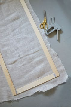 scissors and plywood are sitting on the table next to a piece of fabric that has been cut in half