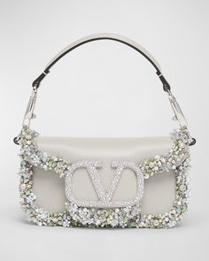 "Find VALENTINO Loco Jeweled Leather Shoulder Bag on Editorialist. The Valentino Garavani \"Loco\" leather shoulder bag features glass jeweled trim. It has a detachable top handle and a detachable chain crossbody strap. It can be worn as a top handle or crossbody bag. The bag has a flap top with a VLOGO magnetic closure. It measures approximately 3.9\"H x 7.9\"W x 2\"D. The bag is made in Italy." Accessories Design Sketch, Fancy Purses, Fashion Trend Board, Valentino Garavani Bag, Rose Bag, Silver Bags, Crystal Bags, Floral Bags, Valentino Bags