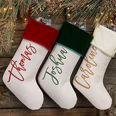 three stockings hanging from a christmas tree with the words merry christmas written on them in gold, green and red