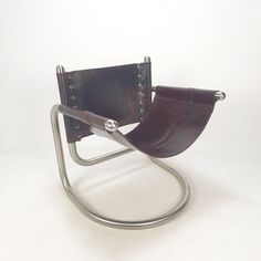 a brown leather chair sitting on top of a metal frame with riveted handles