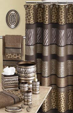 the bathroom is decorated in brown and beige colors with zebra print shower curtain, toiletries, towels, and bath mats