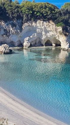 the water is crystal blue and clear with white cliffs in the background at this beach