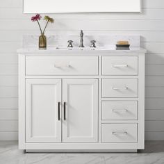 a white bathroom vanity with marble top and drawers