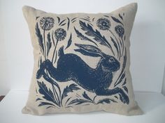 a blue and white pillow with an image of a rabbit in the grass on it