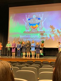 several people standing on stage in front of a large screen with the words northern light spot awards ceremony