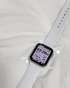 an apple watch sitting on top of a white cloth covered tablecloth with hearts around it