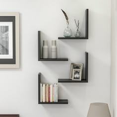 three black floating shelves on the wall above a bed with a lamp and other items